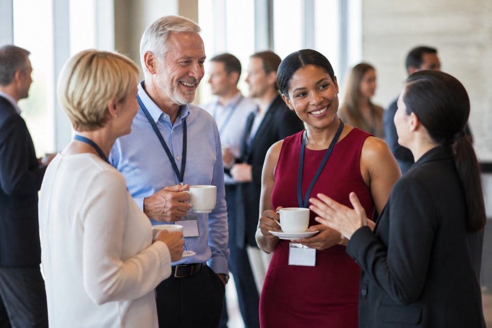 Member retention strategies best practices for 2026 content 1 1790599009 | Zzeem Professional Association Members Engaged in Discussion at a Networking Event, Standing with Coffee Cups and Name Badges Visible, Natural Office Lighting
